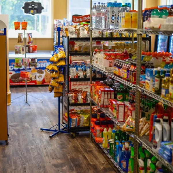 A convenience store aisle with shelves stocked with snacks, drinks, and household items.